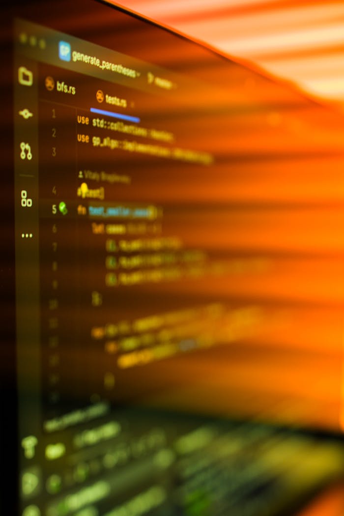 footer-cta Vibrant, motion-blurred view of programming code on a computer screen with an abstract orange glow.